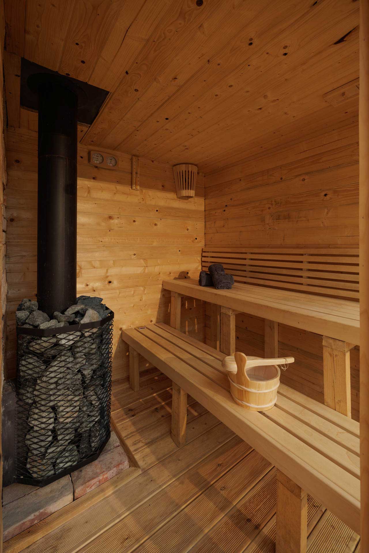 An outdoor wood-fired finish sauna interior. Wood-fired stove by Stoveman.